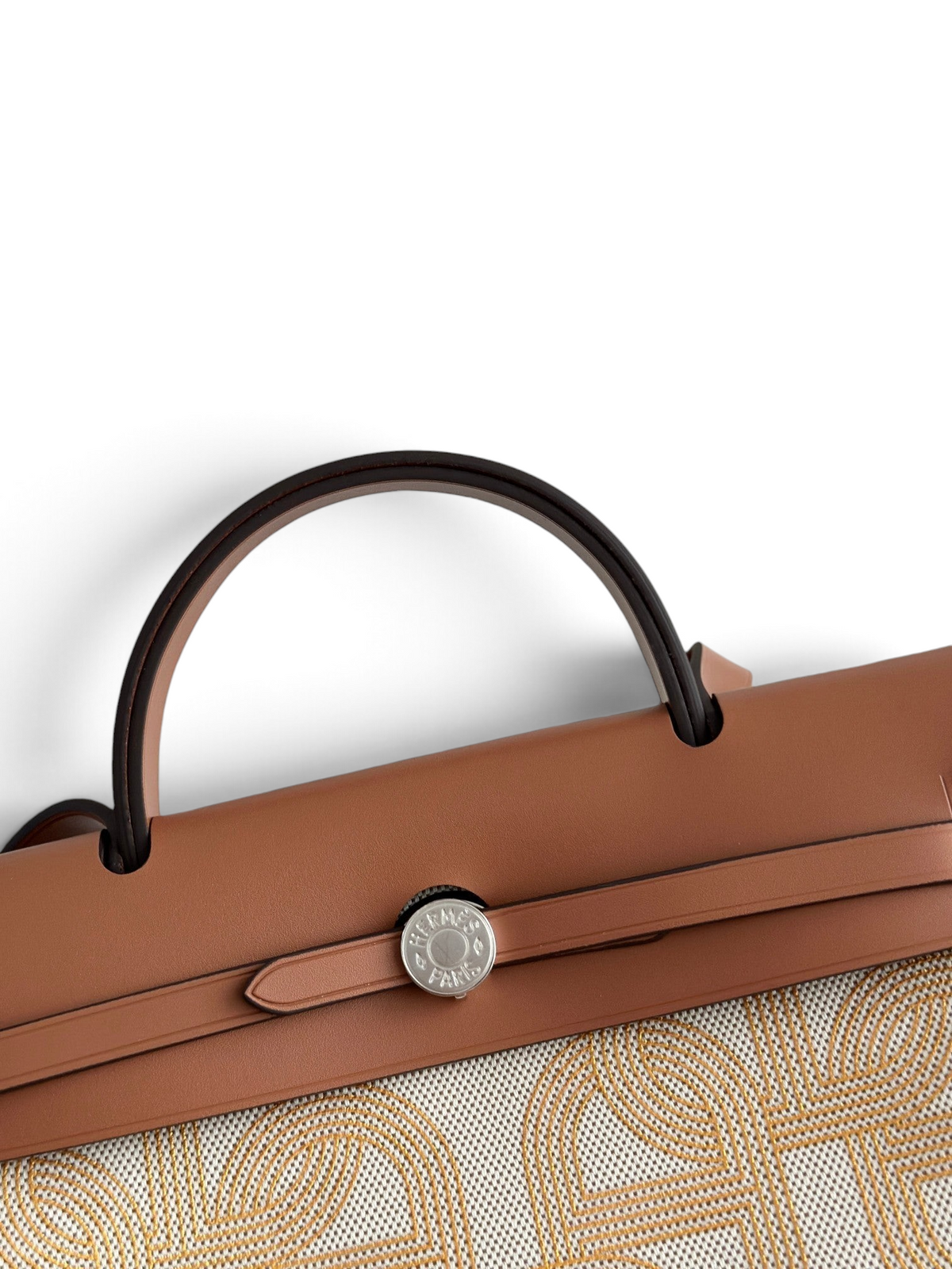SWORD LUXURY Herbag 31 çanta, taba rengi deri kapaklı, Clou de Selle kilitli ve desenli kanvas gövdeli zarif tasarım.