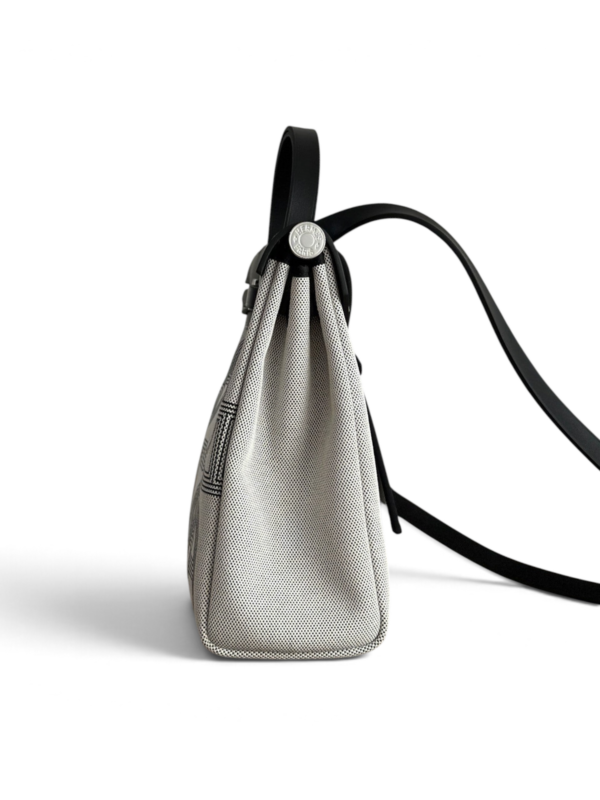 SWORD LUXURY Hermès Herbag 31 çanta, siyah deri detaylı ve desenli kanvas gövdeli, yan profilden görünüm.