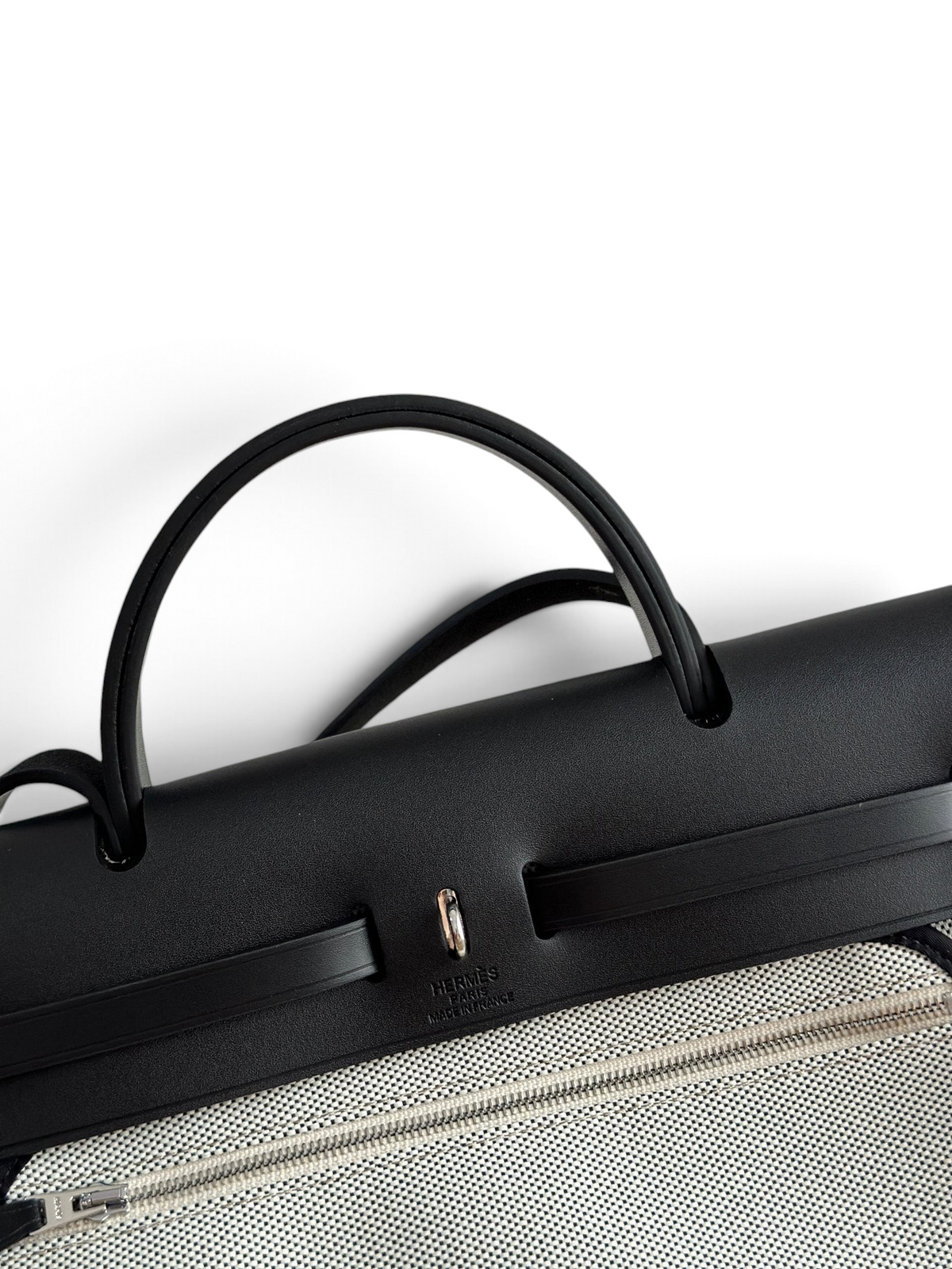 SWORD LUXURY Hermès Herbag 31 çanta, siyah deri kapaklı ve Clou de Selle kilit detaylı, şık kanvas gövde tasarımı.