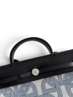 SWORD LUXURY Hermès Herbag 31 çanta, siyah deri kapaklı, Clou de Selle kilitli ve desenli kanvas gövdeli zarif tasarım.