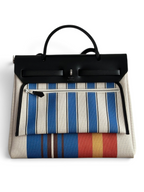 SWORD LUXURY Hermès Herbag 31 çanta, çizgili kanvas gövde, siyah deri kapak ve Clou de Selle detaylı şık tasarım.
