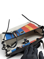 SWORD LUXURY Hermès Herbag 31 çanta, renkli çizgili kanvas gövde ve siyah deri detaylara sahip, üstten açık görünüm.