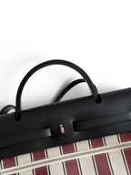 SWORD LUXURY Hermès Herbag 31 siyah deri kapaklı ve çizgili kanvas gövdeli şık el çantası detayı