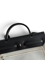 SWORD LUXURY Hermès Herbag 31 çanta, siyah deri kapaklı ve bej kanvas gövdeli, şık ve yapılandırılmış tasarım.