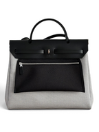 SWORD LUXURY Hermès Herbag 31 çanta, siyah deri kapaklı ve desenli kanvas gövdeli, şık ve yapılandırılmış tasarım.