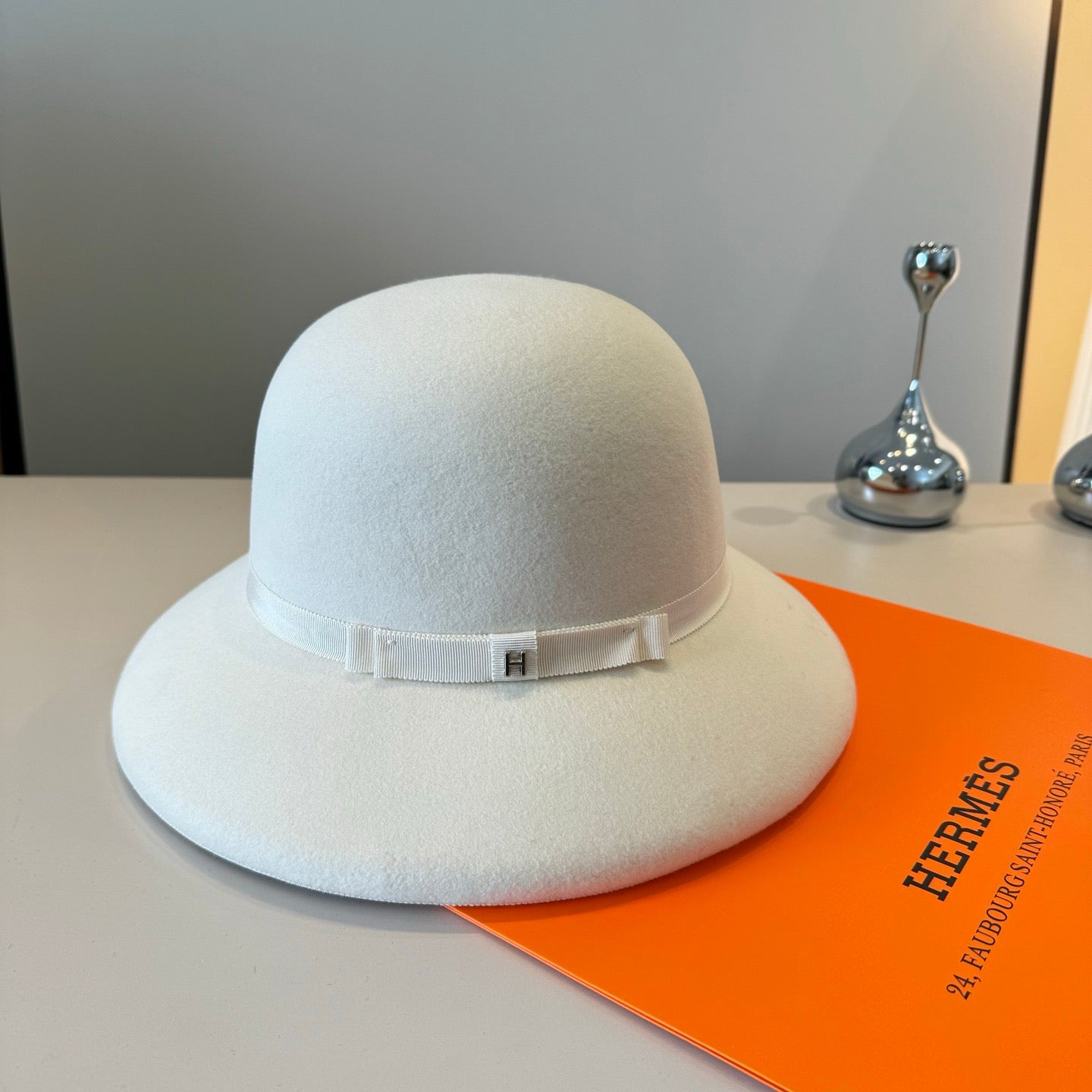 White hat on an orange Hermès box with a gray background