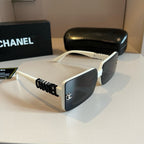 Chanel sunglasses with white frame and black lenses on a reflective surface, with a Chanel box in the background.