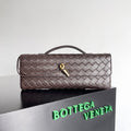 Quilted handbag with gold clasp on a reflective surface with Bottega Veneta branding.
