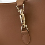SWORD LUXURY Gucci Jackie 1961 küçük hobo çanta, pürüzsüz kahverengi deri ve ikonik altın rengi piston kilit detayı.