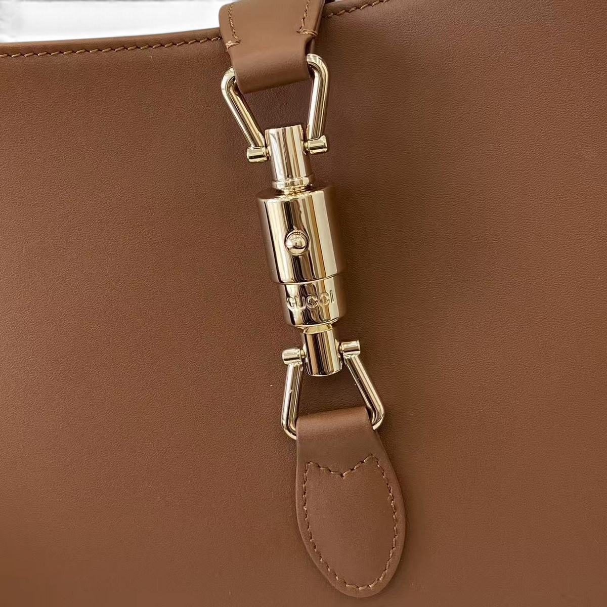 SWORD LUXURY Gucci Jackie 1961 küçük hobo çanta, pürüzsüz kahverengi deri ve ikonik altın rengi piston kilit detayı.