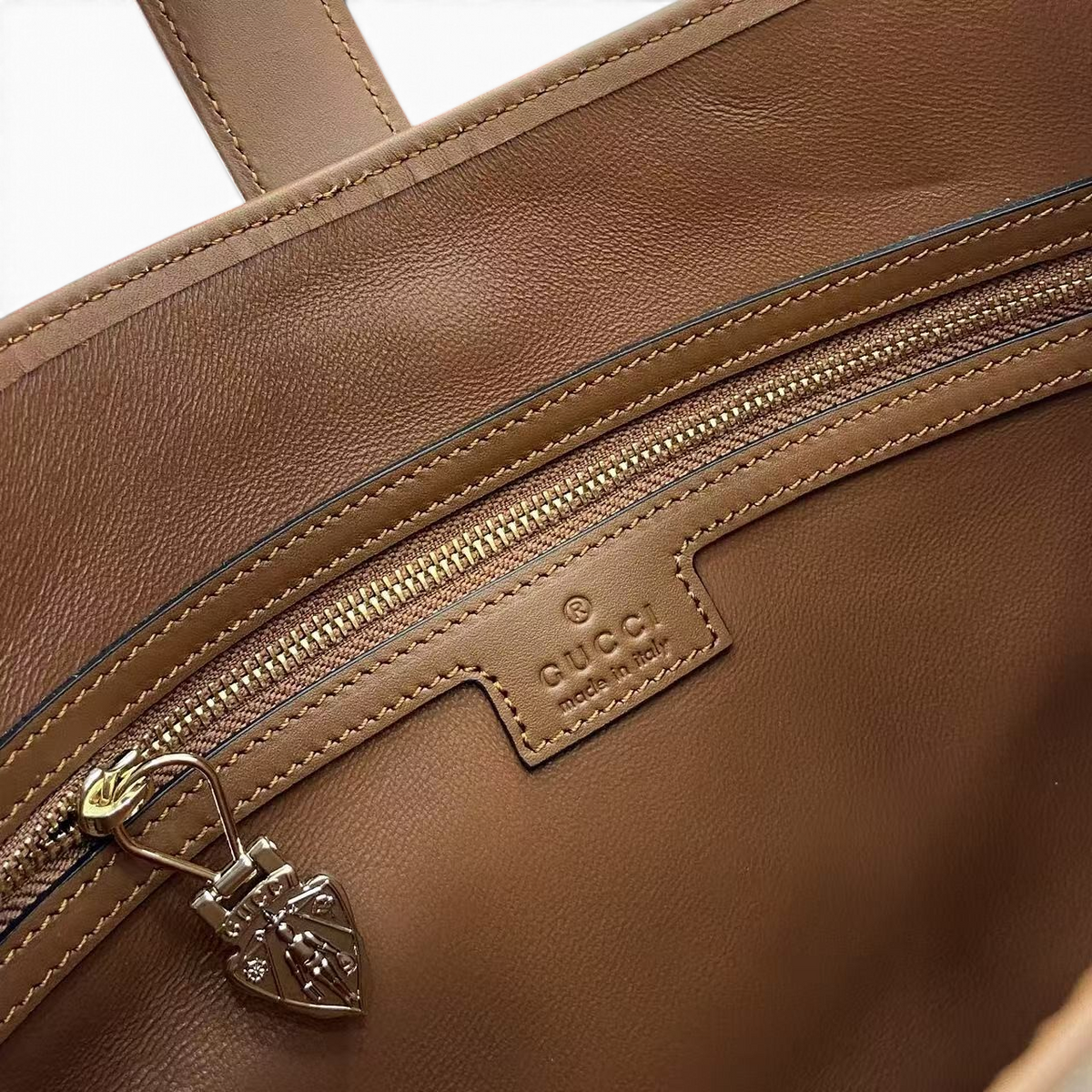 SWORD LUXURY Gucci Jackie 1961 çanta iç detayı, kahverengi deri astar, fermuarlı cep ve Gucci marka etiketi.