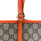 SWORD LUXURY Gucci GG Supreme kanvas çanta, canlı turuncu deri detaylar ve ayarlanabilir tokalı sap ile detaylandırılmış.