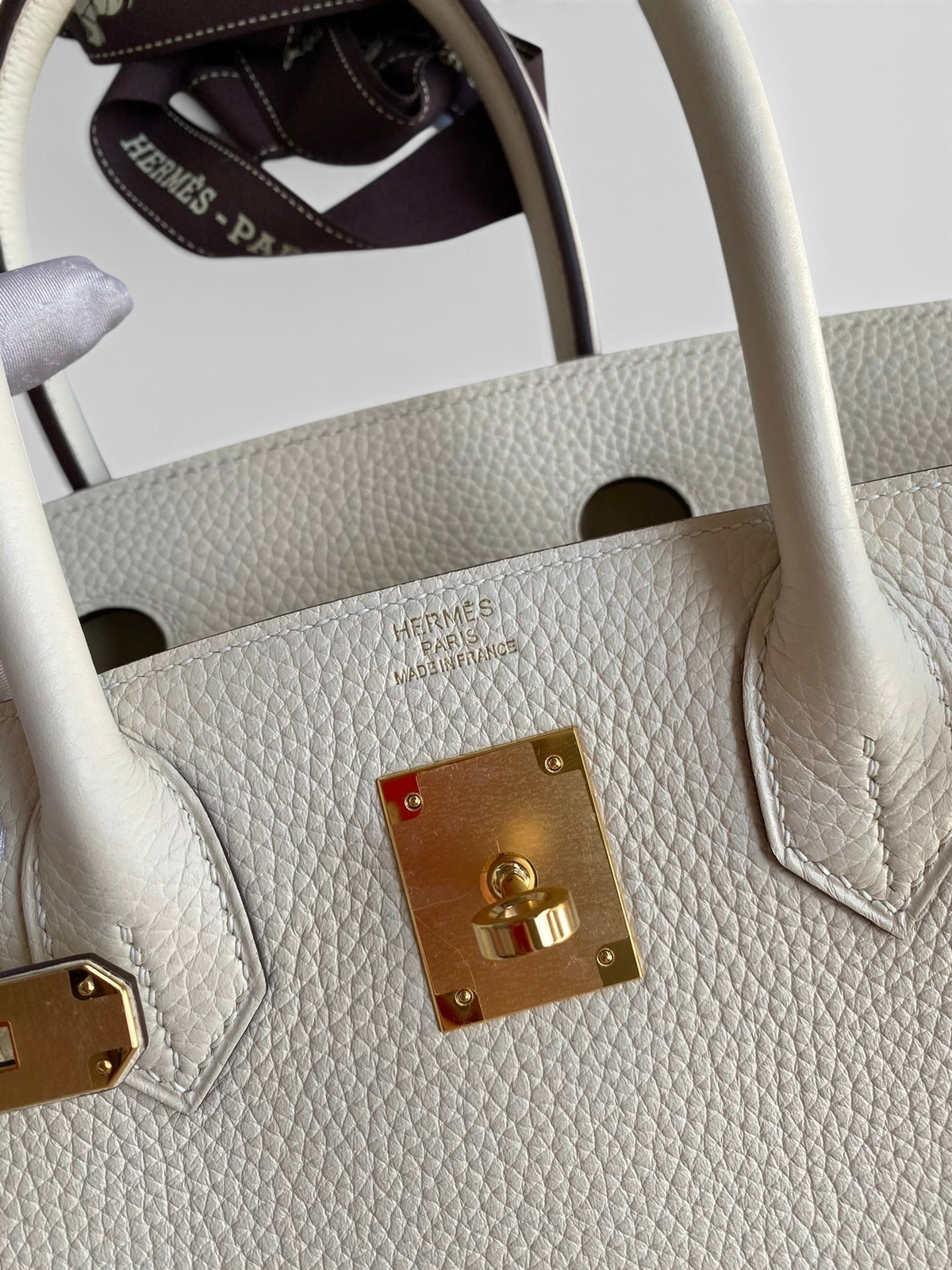 SWORD LUXURY imzalı, altın donanımlı ve beyaz Togo deri detaylı Hermès Birkin 30 el çantası yakın çekimi.