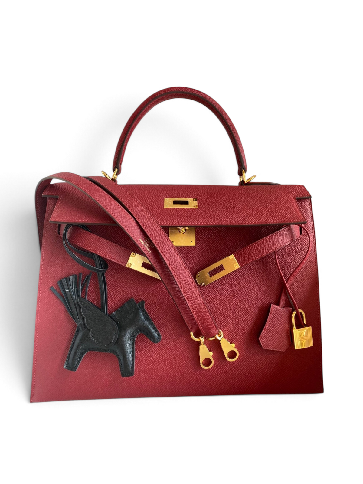 SWORD LUXURY marka, kırmızı Epsom deri Hermès Kelly 32cm çanta, altın donanım ve siyah at figürlü çanta aksesuarı ile.