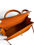 SWORD LUXURY marka turuncu Epsom deri Hermès Kelly 32cm çanta, iç bölmesi ve altın rengi kilit detaylarıyla kutusunda.