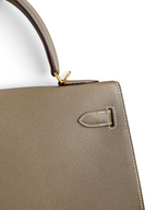 SWORD LUXURY marka, taupe renkli, dokulu Epsom deri Hermès Kelly 32cm çanta detayı ve altın tonlu donanımı.
