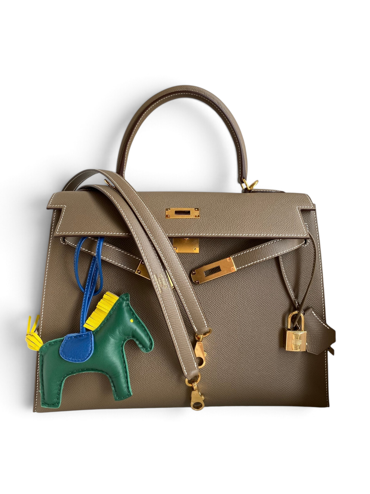 SWORD LUXURY marka, 32 cm boyutunda, taupe renkli Epsom deri Hermès Kelly çanta, altın donanım ve at figürlü çanta süsü ile.