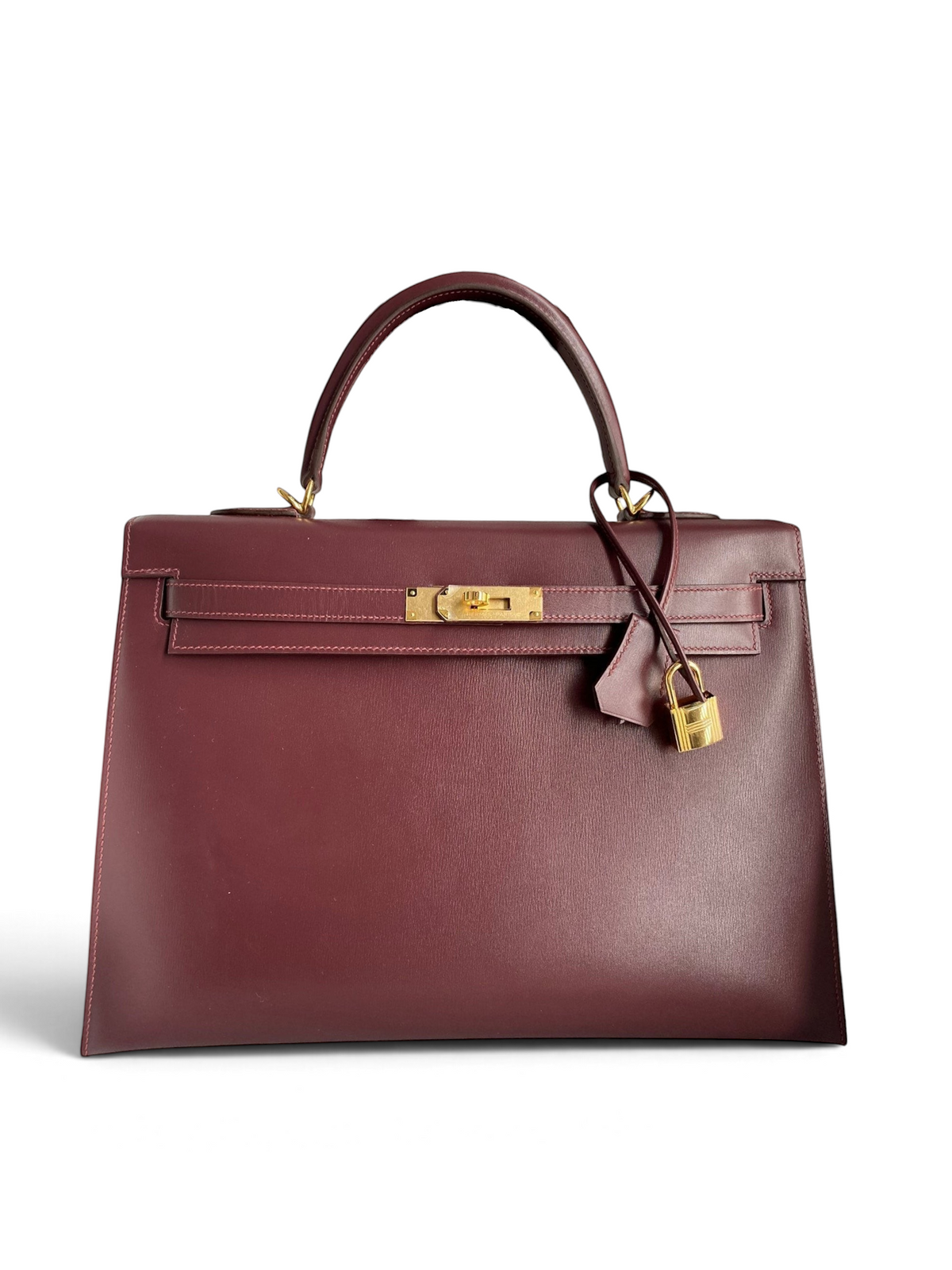 SWORD LUXURY marka, bordo renkli, altın donanımlı ve kilit detaylı 32 cm Hermès Kelly kutu deri el çantası.