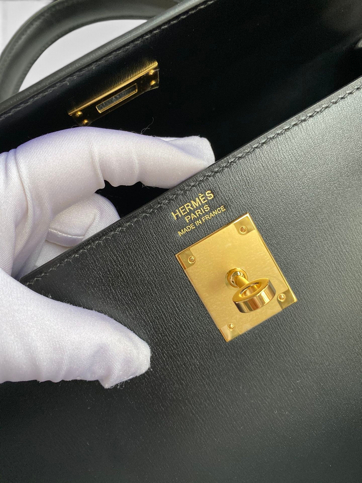 SWORD LUXURY Hermès Kelly 32cm çanta, altın rengi kilit detayı ve pürüzsüz siyah box deri dokusu ile detaylı görünüm.