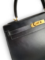 SWORD LUXURY imzalı, altın donanımlı ve ikonik kilit detayına sahip siyah deri Hermès Kelly 32cm el çantası.
