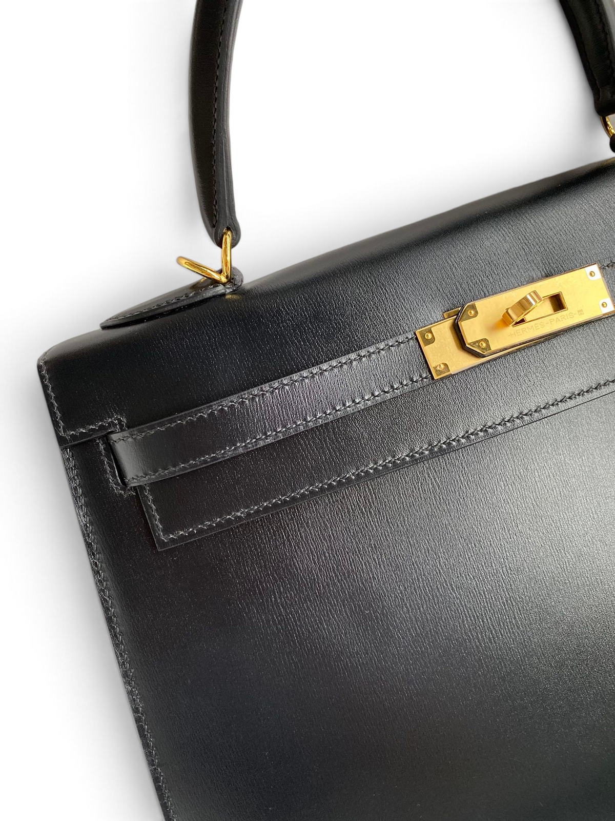SWORD LUXURY imzalı, altın donanımlı ve ikonik kilit detayına sahip siyah deri Hermès Kelly 32cm el çantası.