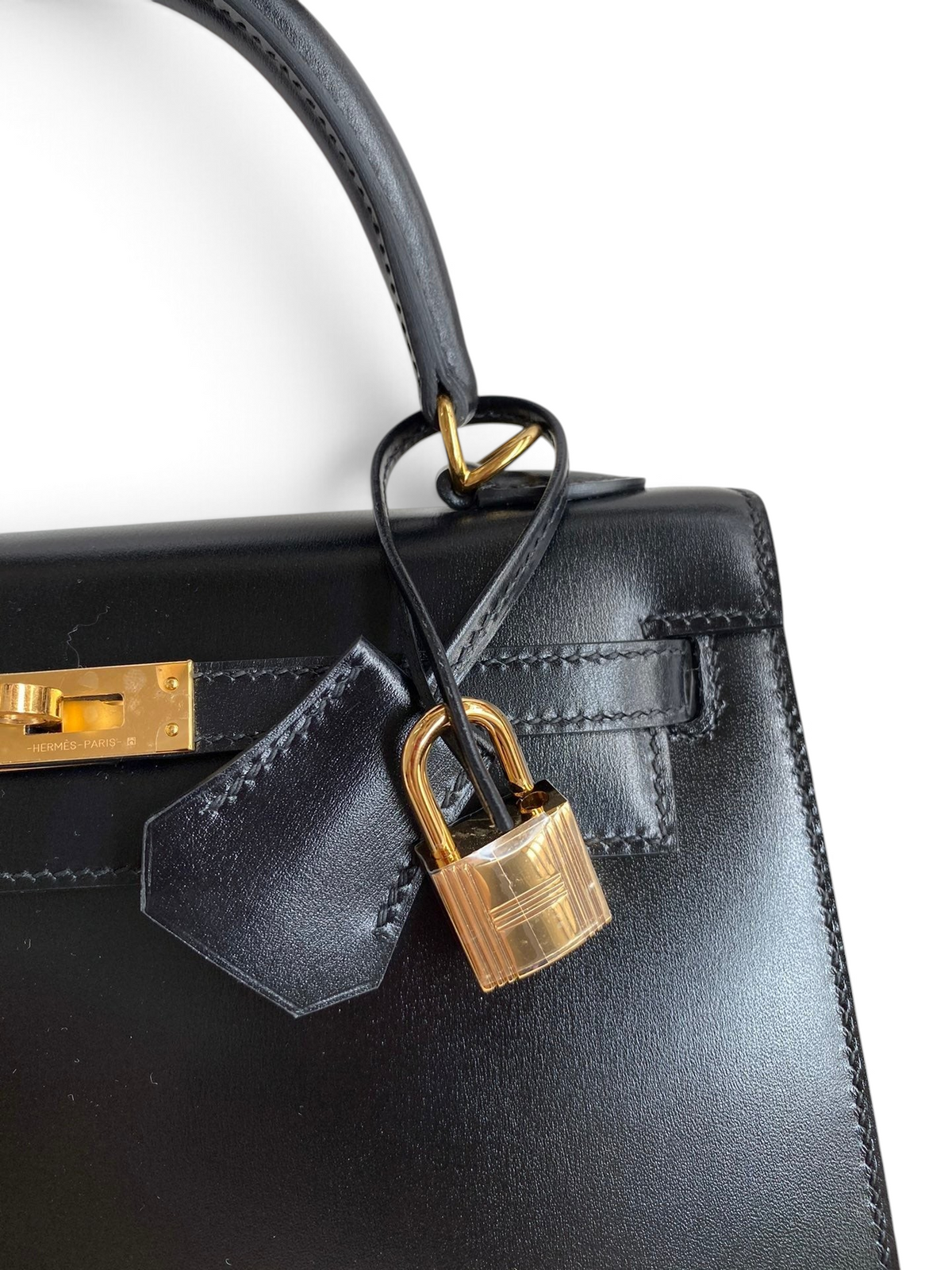 SWORD LUXURY imzalı, altın donanımlı ve kilit detaylı siyah box deri Hermès Kelly 25cm çanta.