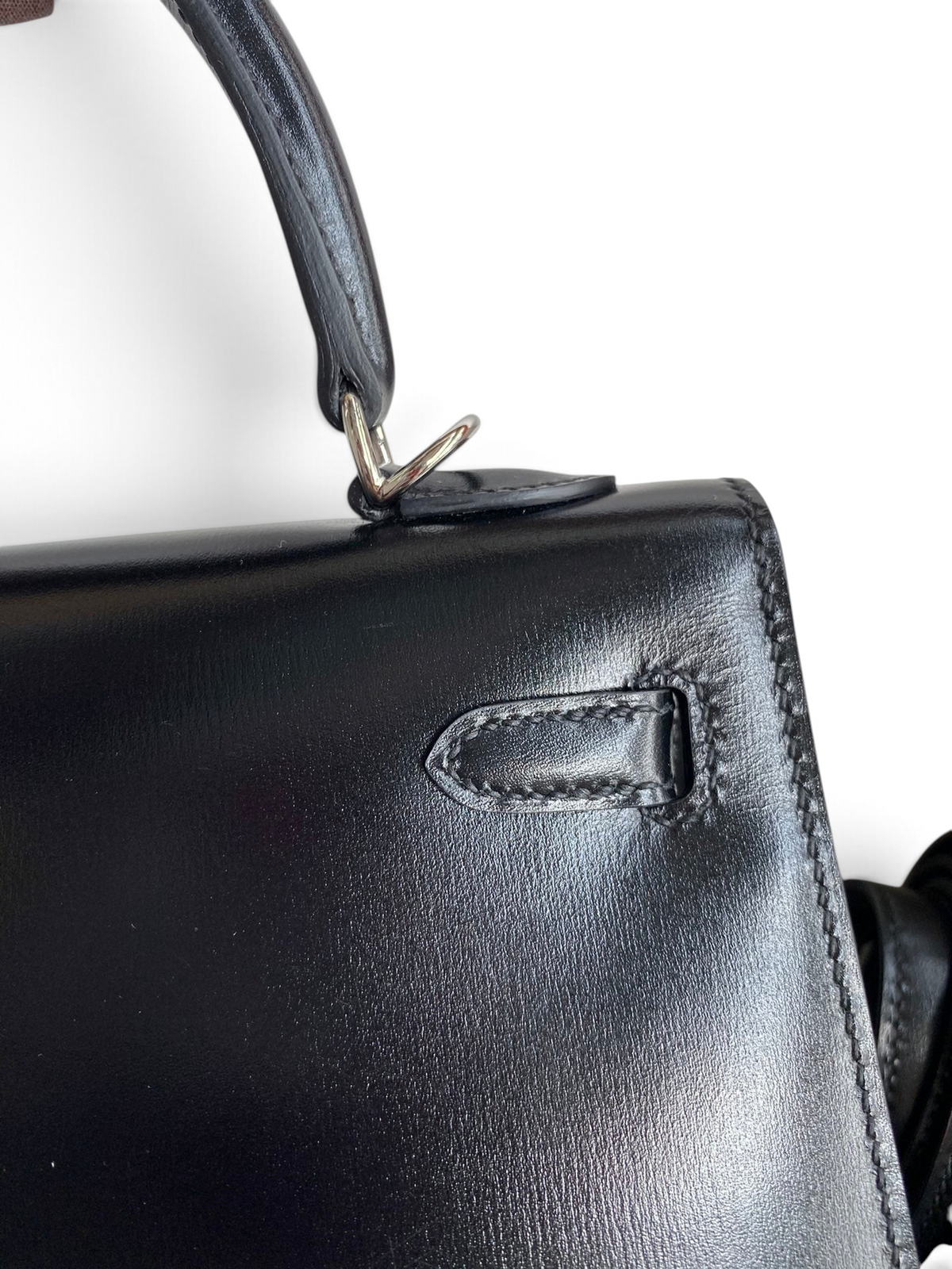 SWORD LUXURY siyah box deri Hermès Kelly 25cm çanta detayı, pürüzsüz deri dokusu ve metalik kilit mekanizması.