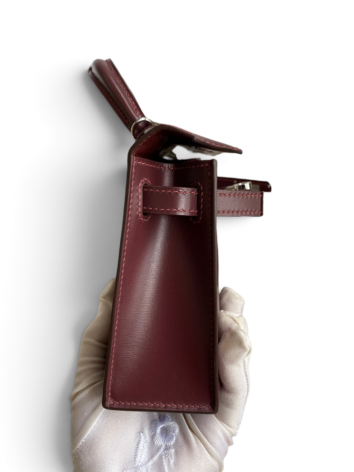 SWORD LUXURY marka bordo renkli, pürüzsüz box deri Hermès Mini Kelly 19cm çanta, yan profil ve detaylı dikiş görünümü.