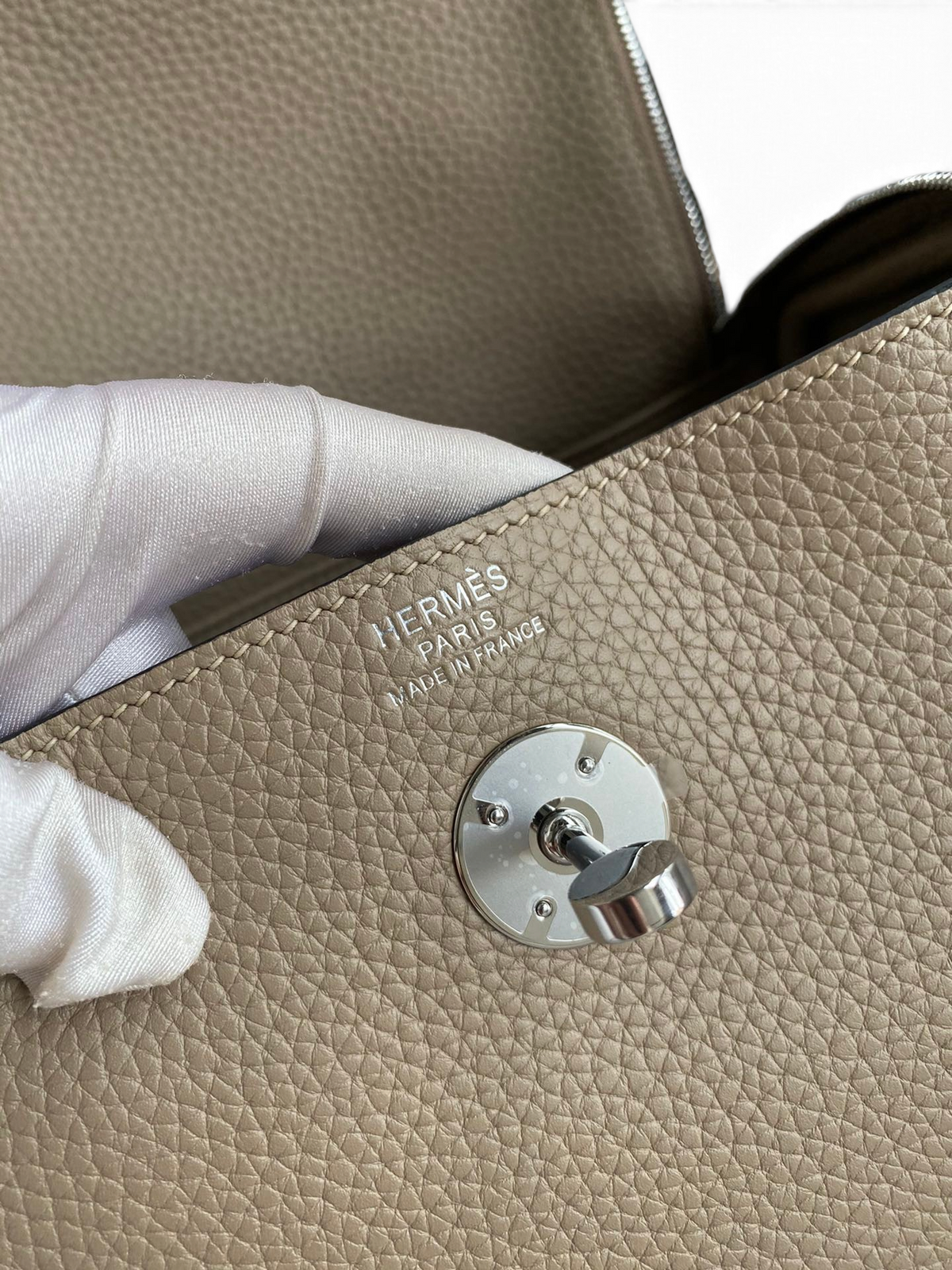 SWORD LUXURY Hermès Lindy 26 çanta, bej renkli Clemence deri dokusu ve gümüş renkli döner kilit detayı.