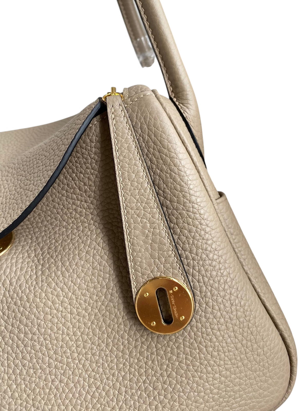 SWORD LUXURY marka, bej rengi Clemence deri Hermès Lindy 26 çanta, altın tonlu metal detaylı ve ikonik kilitli tasarım.