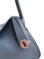 SWORD LUXURY lacivert Clemence deri Hermès Lindy 26 çanta, gümüş tonlu metal kilit detayı ile yakın çekim.