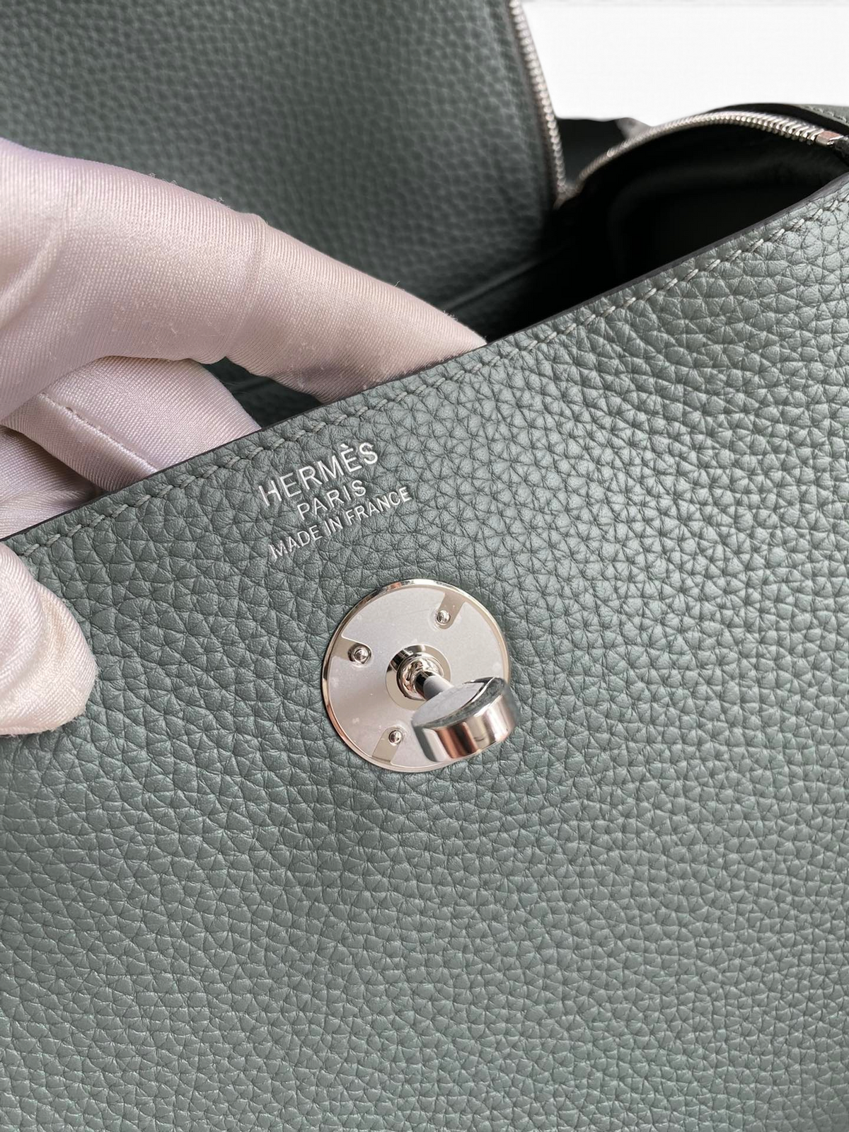 SWORD LUXURY Hermès Lindy 26 çanta, gri Clemence deri dokusu, metalik döner kilit detayı ve iç damga logosu.
