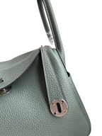 SWORD LUXURY Hermès Lindy 26 çanta, yeşil Clemence deri detayları, gümüş donanım ve ikonik döner kilit mekanizması.
