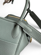 SWORD LUXURY Hermès Lindy 26 çanta, gri Clemence deri dokusu, üst sapları ve omuz askısı detaylarıyla yakın çekim.