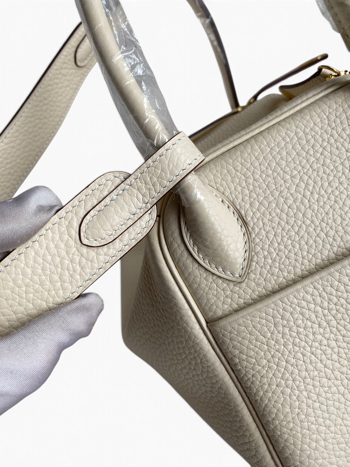 SWORD LUXURY marka, krem rengi Clemence deri Hermès Lindy 26 çanta detayı, omuz askısı ve dokulu deri yüzeyi.