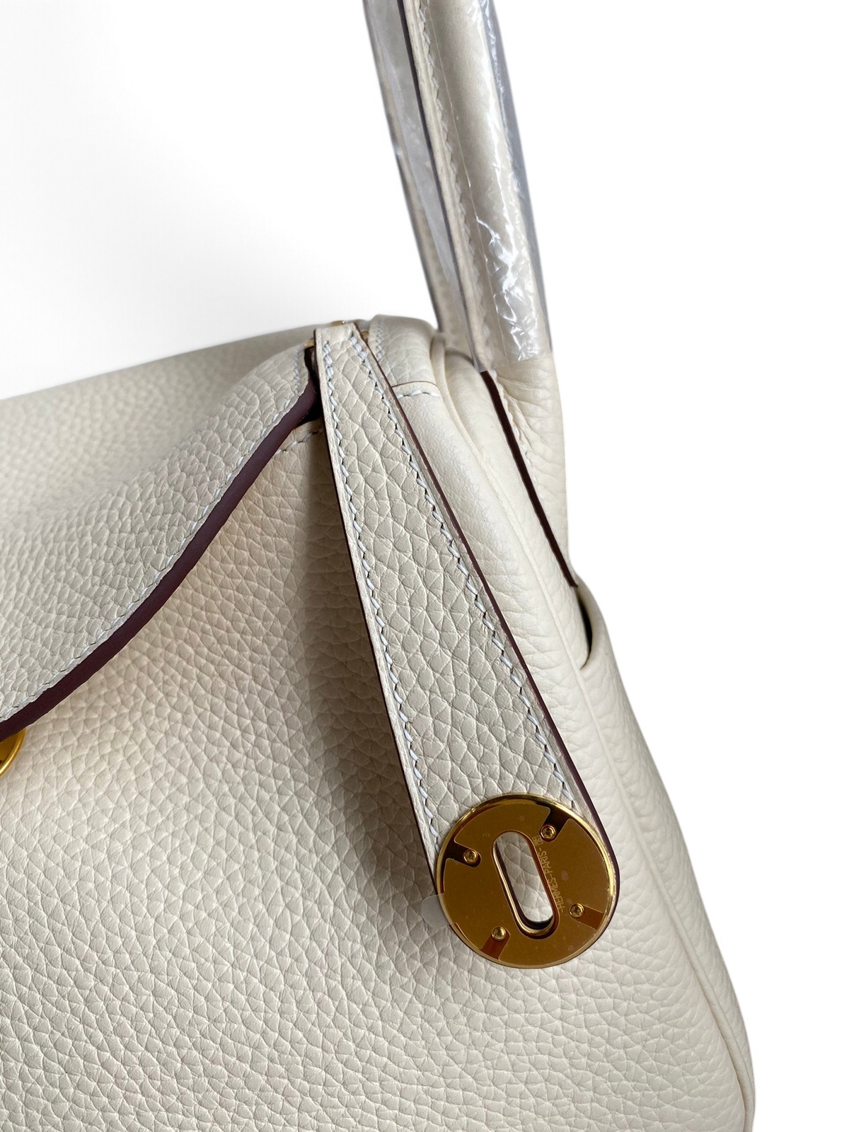 SWORD LUXURY beyaz Clemence deri Hermès Lindy 26 çanta, altın tonlu metal detaylı ve ikonik döner kilitli tasarım.
