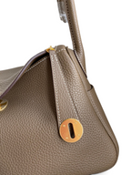 SWORD LUXURY Lindy 26 çanta, altın donanımlı, taupe renkli, dokulu Clemence deri detaylı ve ikonik kilit mekanizmalı.