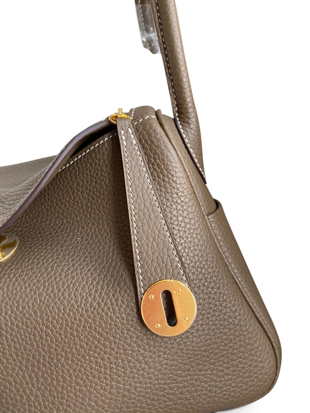 SWORD LUXURY Lindy 26 çanta, altın donanımlı, taupe renkli, dokulu Clemence deri detaylı ve ikonik kilit mekanizmalı.