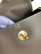 SWORD LUXURY Hermès Lindy 26 çanta, altın rengi kilit detayı ve dokulu Clemence deri yüzeyi ile yakın çekim.