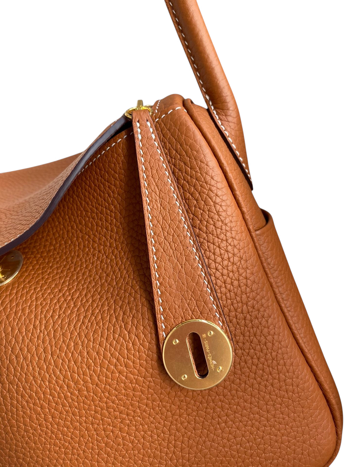SWORD LUXURY marka taba rengi Clemence deri Hermès Lindy 26 çanta, altın donanım ve dikiş detayları ile yakın çekim.