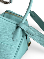 SWORD LUXURY turkuaz renkli, Clemence deri Hermès Lindy 26 çanta, detaylı dokusu ve altın tonlu metal aksesuarlarıyla.