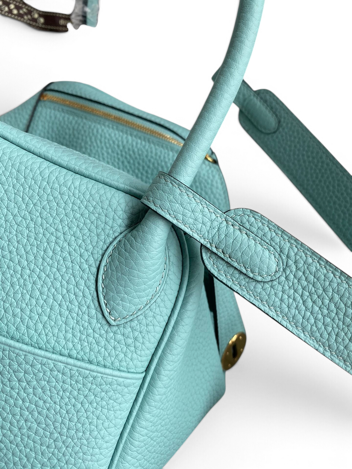 SWORD LUXURY turkuaz renkli, Clemence deri Hermès Lindy 26 çanta, detaylı dokusu ve altın tonlu metal aksesuarlarıyla.