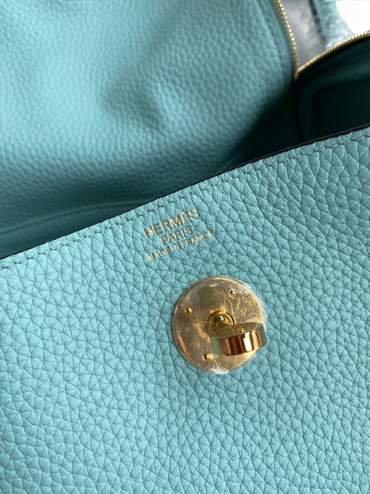 SWORD LUXURY Hermès Lindy 26 çanta detayında altın rengi kilit mekanizması ve turkuaz Clemence deri dokusu