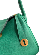 SWORD LUXURY Hermès Lindy 26 çanta, yeşil Clemence deri detayları ve altın rengi metal kilit mekanizması ile.