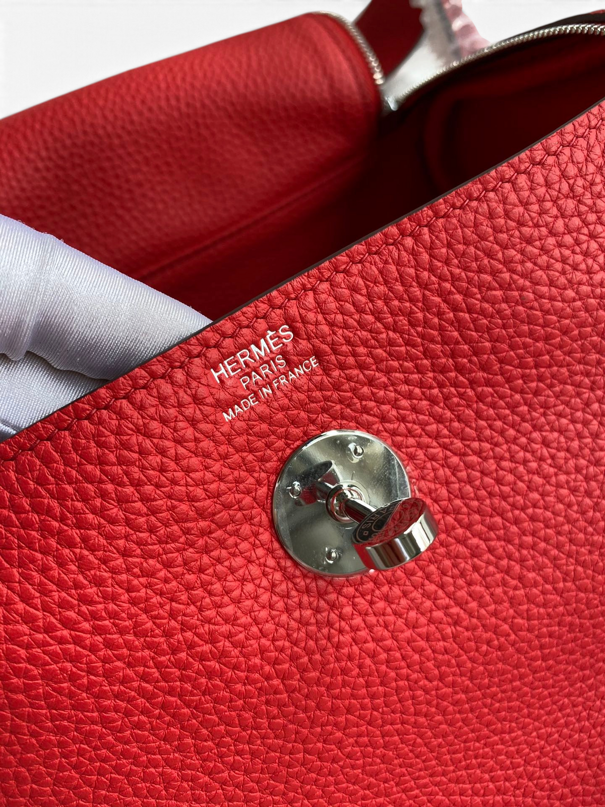 SWORD LUXURY Hermès Lindy 26 çanta, kırmızı Clemence deri dokusu ve gümüş renkli döner kilit detayı ile yakından görünüm