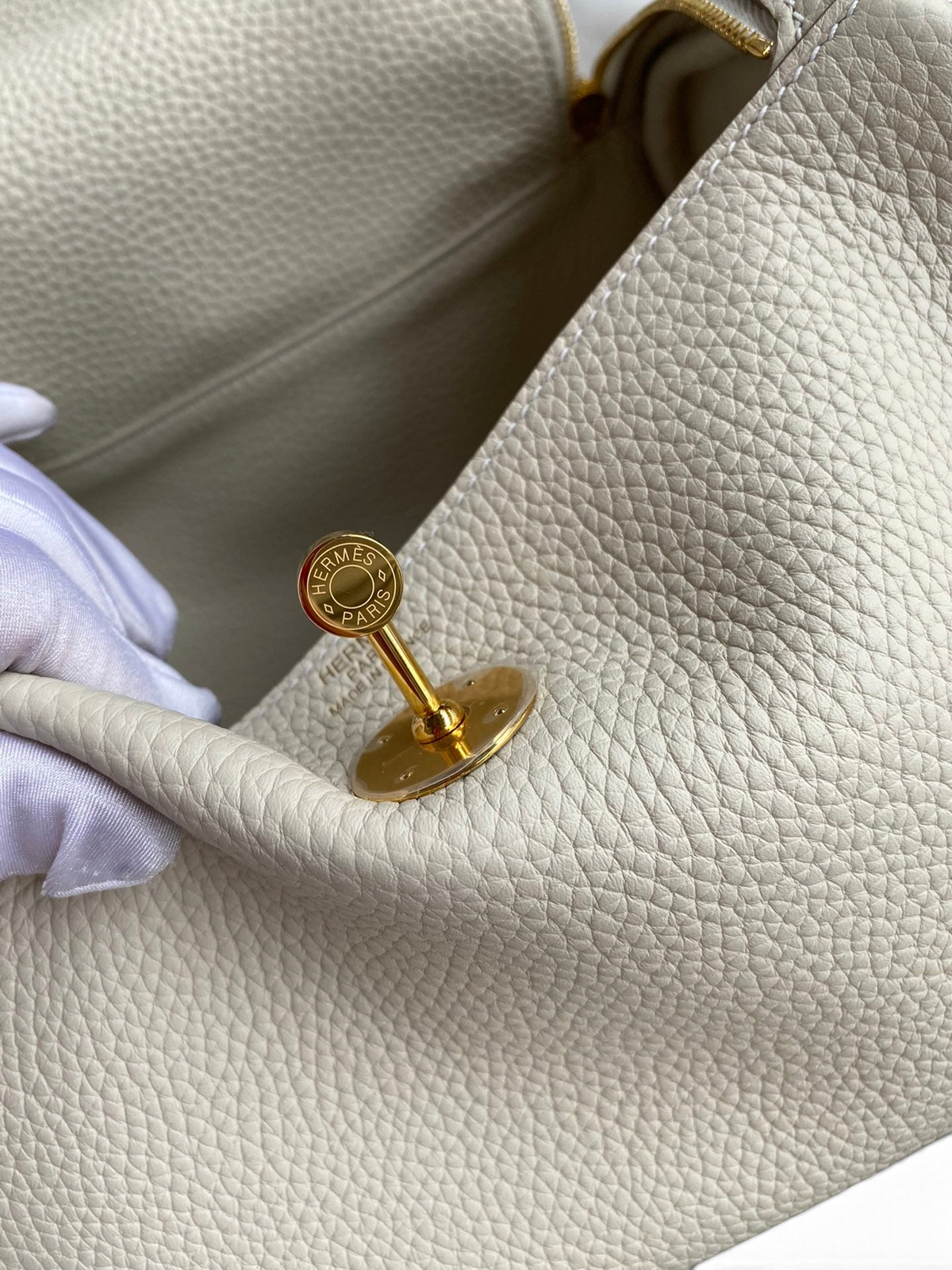 SWORD LUXURY marka, krem rengi Clemence deri Hermès Lindy 26 çanta, altın tonlu metal döner kilit detayı ile.