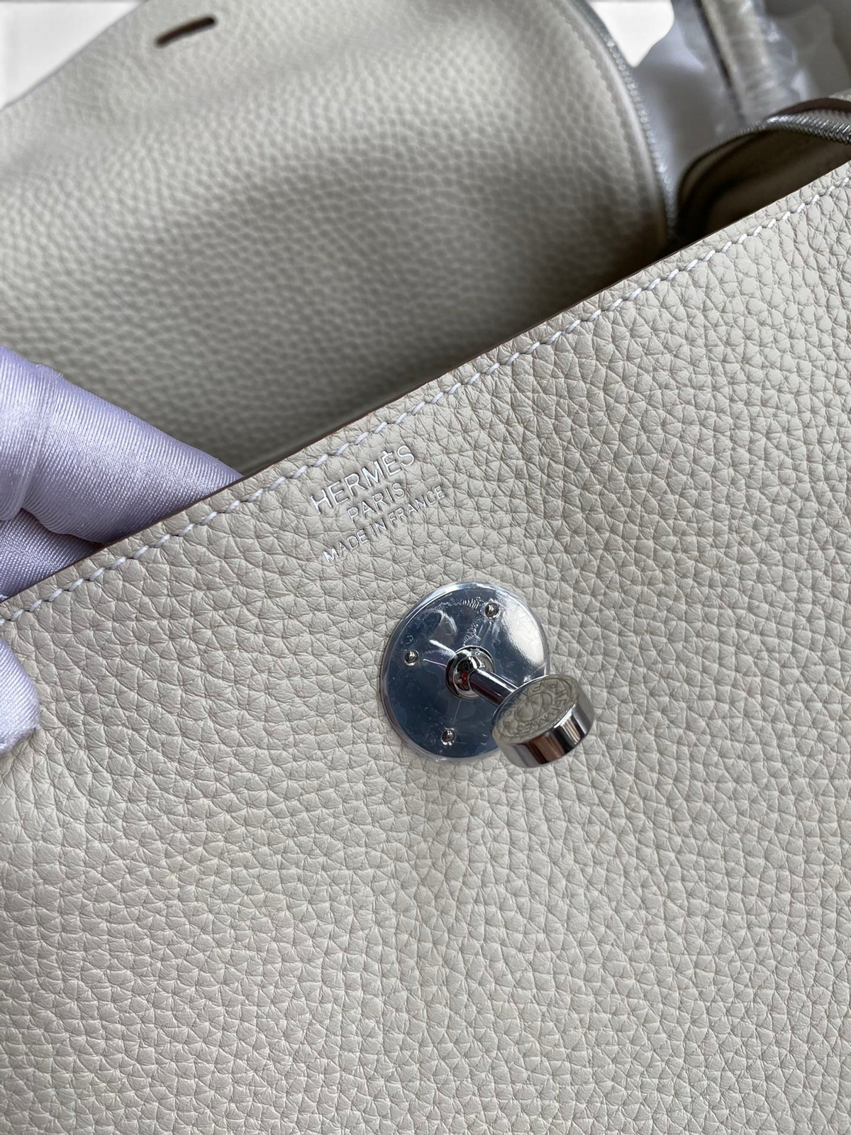 SWORD LUXURY Hermès Lindy 26 çanta, gümüş donanımlı krem rengi Clemence deri detayları ve ikonik döner kilit mekanizması.